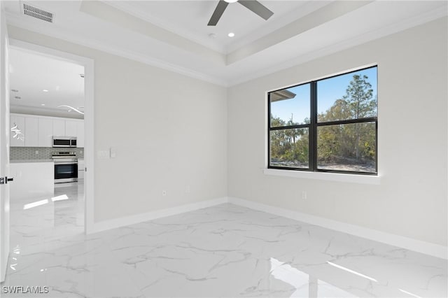 empty room with crown molding, a tray ceiling, and ceiling fan