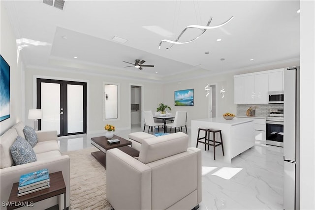 living room with marble finish floor, a raised ceiling, visible vents, and crown molding