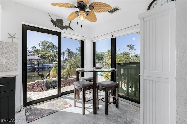 sunroom / solarium with ceiling fan, a water view, and a healthy amount of sunlight