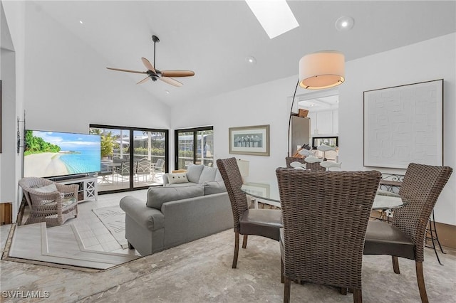 living room featuring ceiling fan, high vaulted ceiling, and a skylight