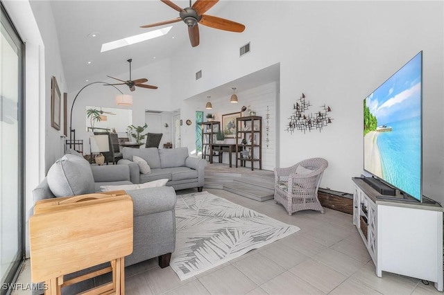 living room with a skylight, high vaulted ceiling, and ceiling fan