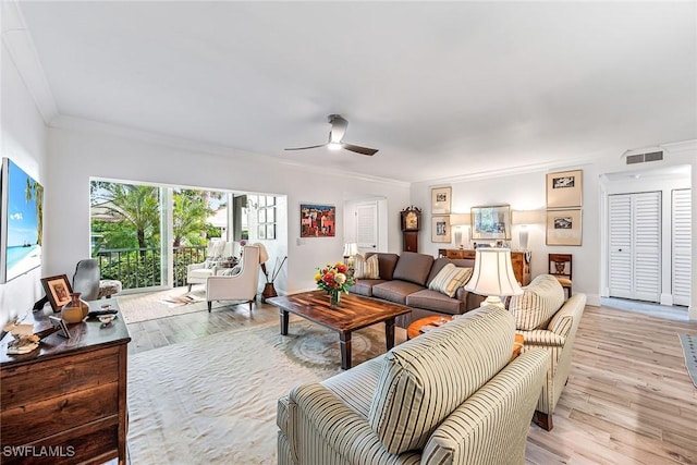 living room with ornamental molding, ceiling fan, and light hardwood / wood-style floors