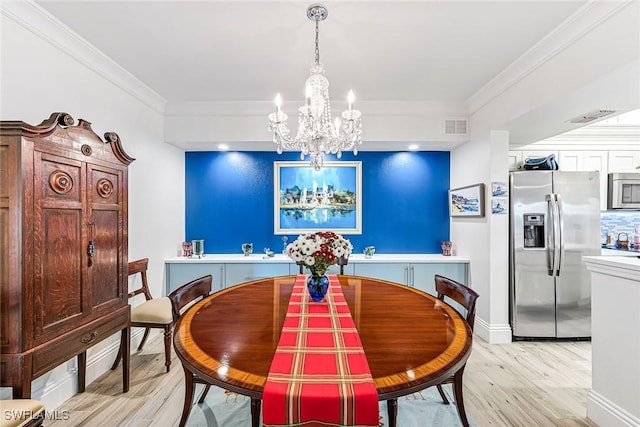 dining space featuring crown molding, a notable chandelier, and light hardwood / wood-style flooring