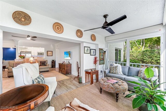 living room featuring a textured ceiling, light hardwood / wood-style flooring, and ceiling fan