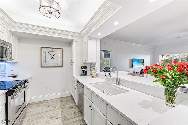 788 Willowbrook Dr Unit 502, Naples, FL 34108 - kitchen featuring stainless steel appliances, a sink, crown molding, baseboards, and white cabinetry