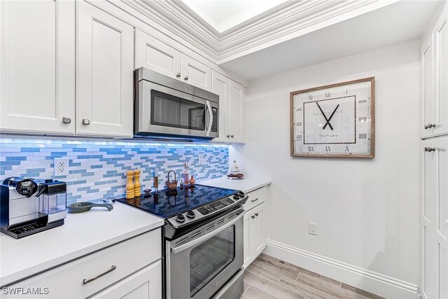 kitchen featuring crown molding, stainless steel appliances, light hardwood / wood-style floors, decorative backsplash, and white cabinets