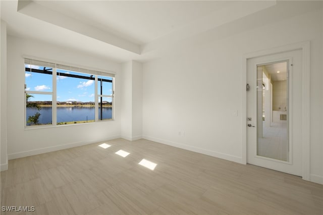 spare room featuring a water view and a tray ceiling