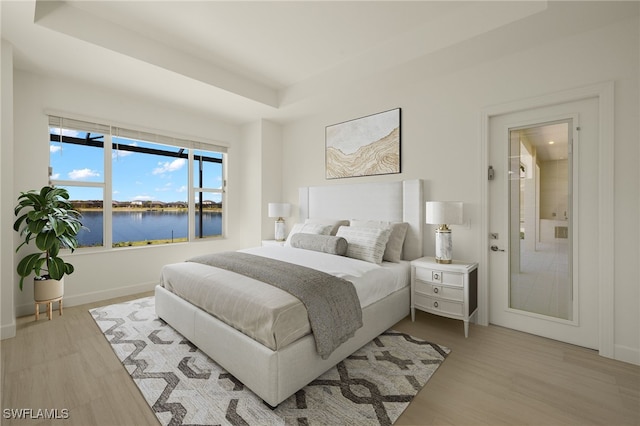 bedroom with a water view and light wood-type flooring