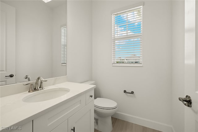 bathroom with hardwood / wood-style flooring, vanity, and toilet