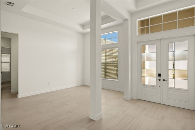 entrance foyer featuring french doors, a tray ceiling, and a high ceiling