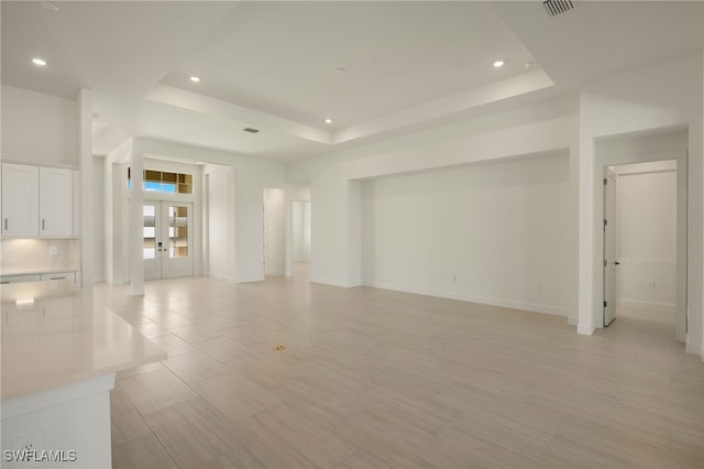 unfurnished living room with french doors and a raised ceiling