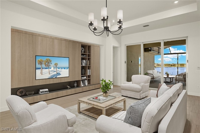 living room featuring a raised ceiling, light hardwood / wood-style flooring, and an inviting chandelier