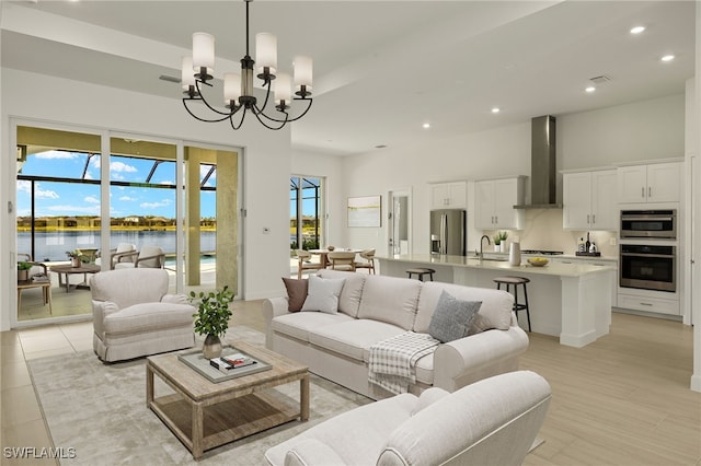 living room with light tile patterned flooring, a water view, sink, and an inviting chandelier