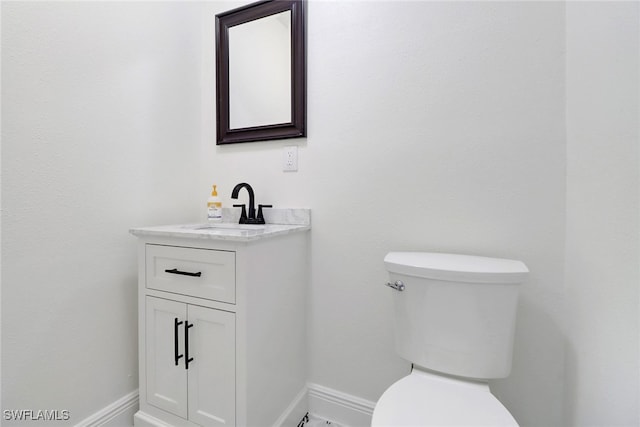 bathroom with baseboards, vanity, and toilet