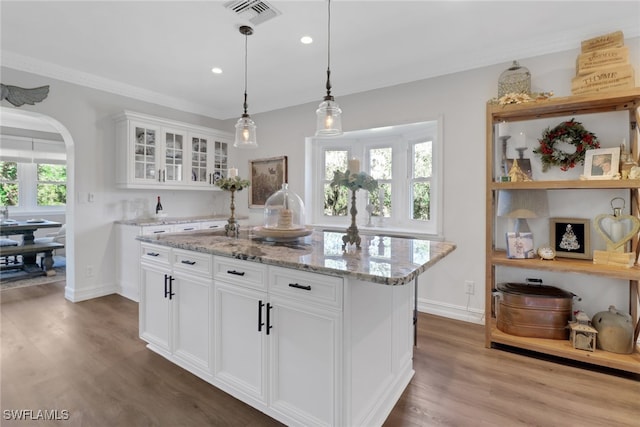 kitchen featuring visible vents, white cabinets, arched walkways, dark wood finished floors, and light stone countertops