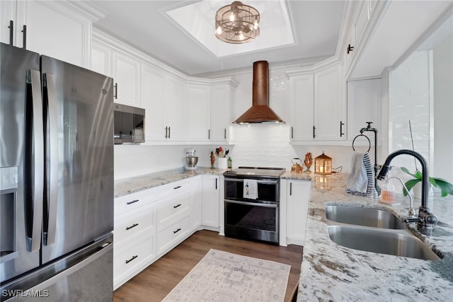 kitchen featuring stainless steel appliances, a sink, white cabinetry, wall chimney exhaust hood, and dark wood finished floors