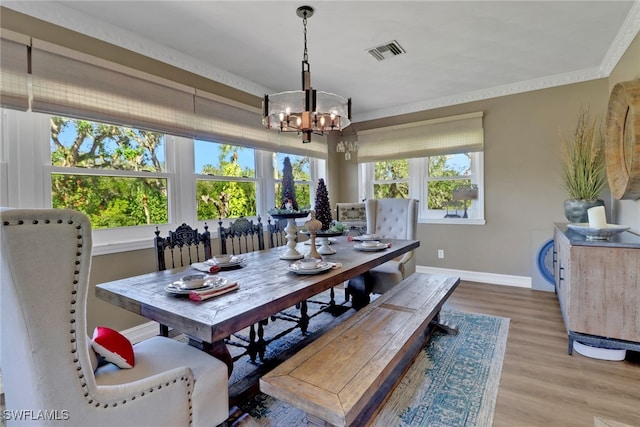 dining area featuring crown molding, visible vents, an inviting chandelier, wood finished floors, and baseboards