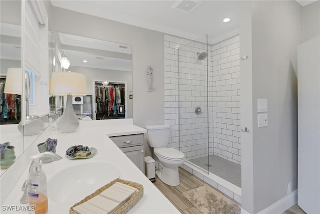 bathroom featuring toilet, a spacious closet, a tile shower, and vanity