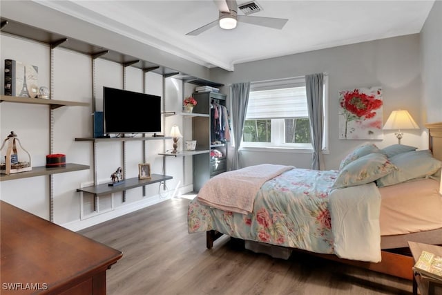 bedroom featuring a ceiling fan, visible vents, and wood finished floors