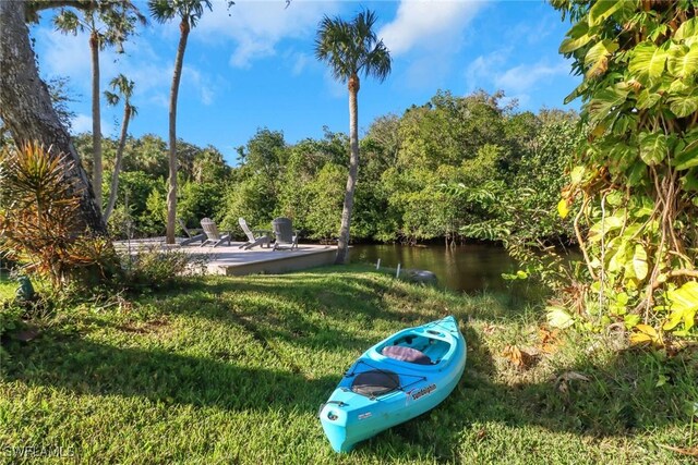 surrounding community with a water view, a patio area, and a lawn