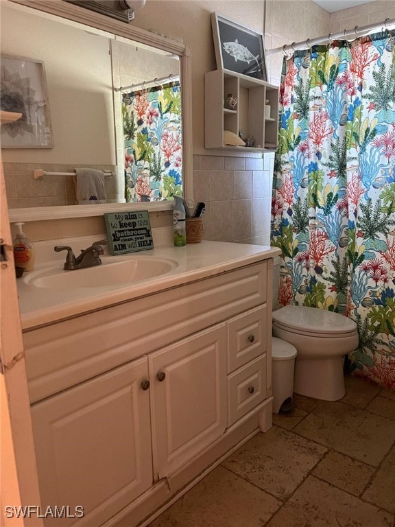 bathroom with a shower with shower curtain, vanity, toilet, and tile walls