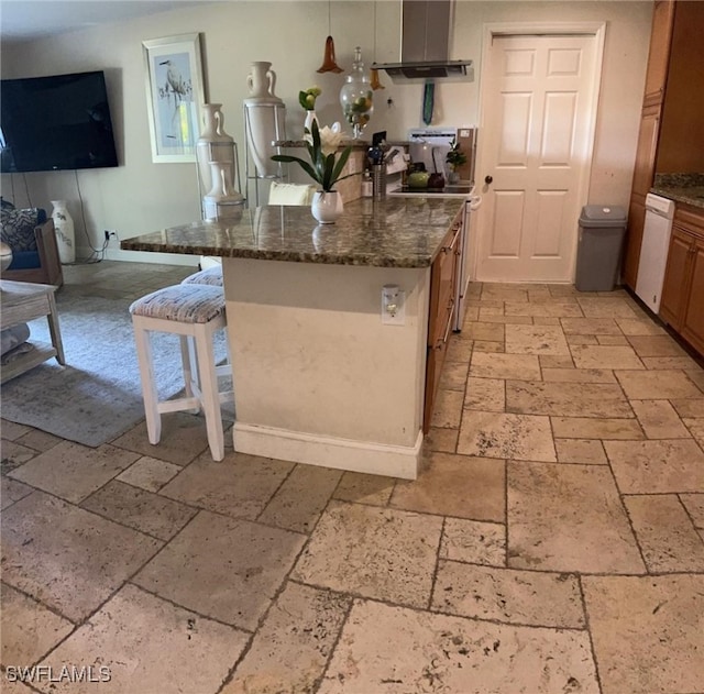 kitchen with white dishwasher, dark stone countertops, decorative light fixtures, island range hood, and a breakfast bar area