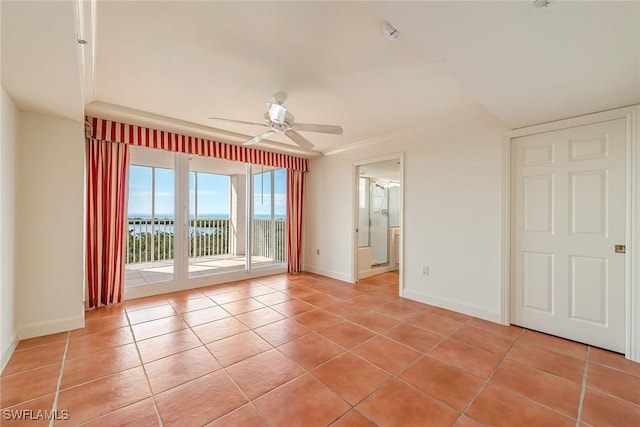 empty room with ceiling fan, a water view, light tile patterned floors, and ornamental molding