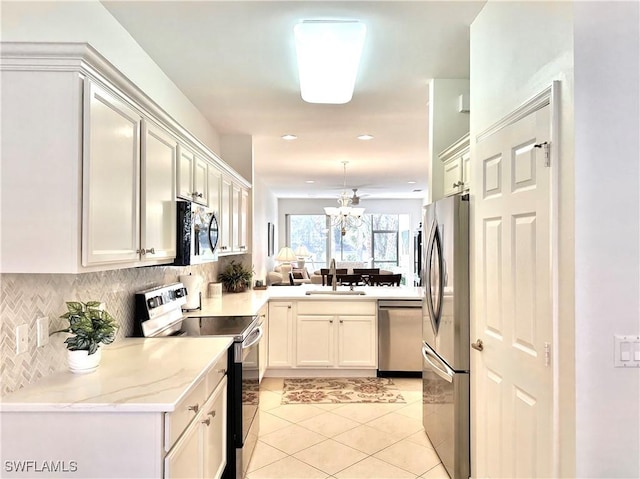 kitchen featuring white cabinetry, kitchen peninsula, decorative backsplash, light tile patterned floors, and appliances with stainless steel finishes