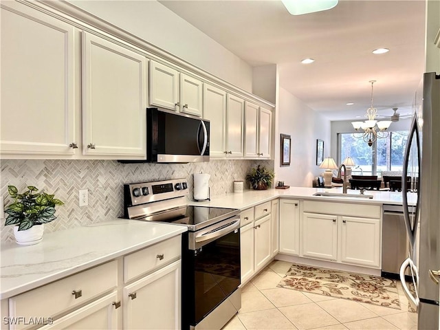 kitchen featuring sink, stainless steel appliances, kitchen peninsula, a chandelier, and light tile patterned floors