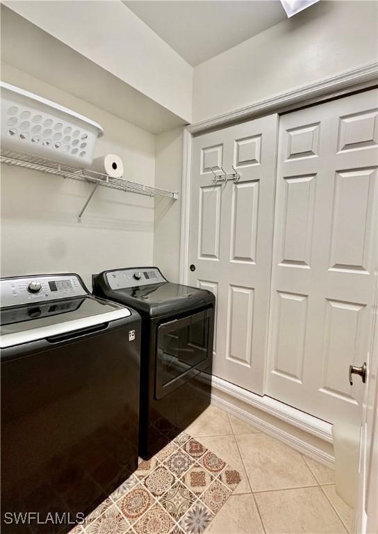 clothes washing area featuring light tile patterned floors and washing machine and clothes dryer