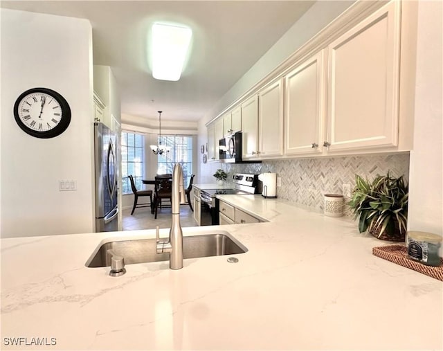 kitchen featuring light stone countertops, hanging light fixtures, and stainless steel appliances