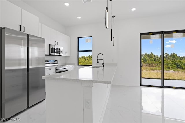 kitchen with sink, hanging light fixtures, kitchen peninsula, white cabinets, and appliances with stainless steel finishes