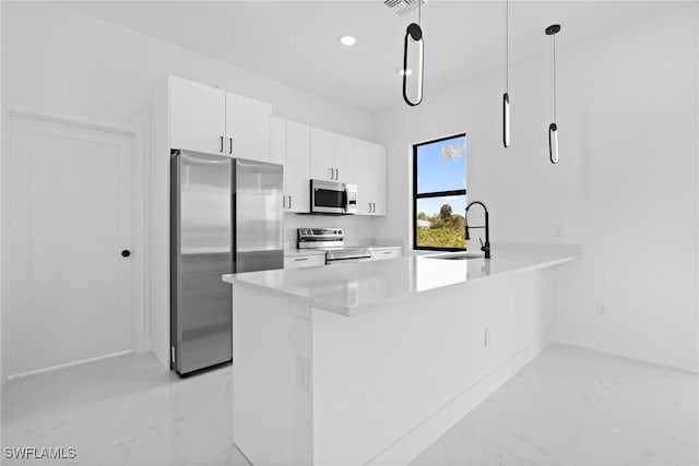 kitchen with kitchen peninsula, stainless steel appliances, sink, decorative light fixtures, and white cabinetry