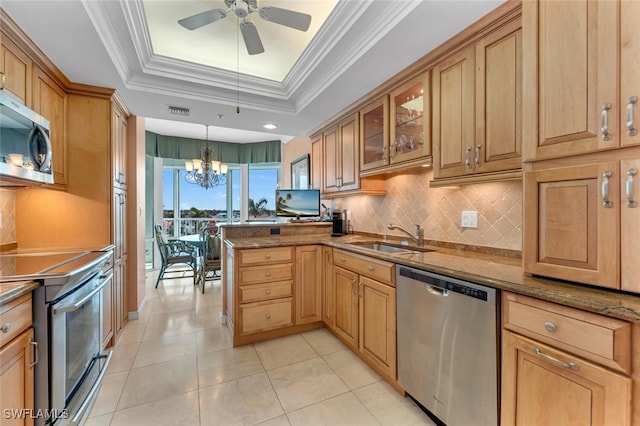 kitchen with appliances with stainless steel finishes, a tray ceiling, sink, decorative light fixtures, and stone counters