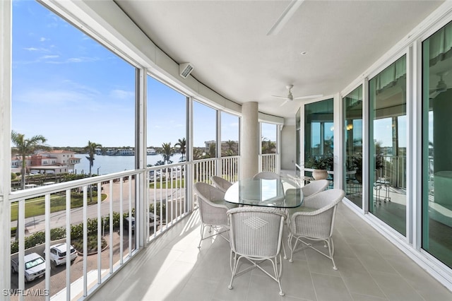 sunroom featuring ceiling fan and a water view