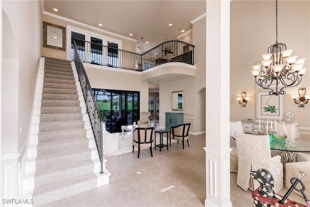 foyer entrance with decorative columns, a chandelier, a high ceiling, and ornamental molding