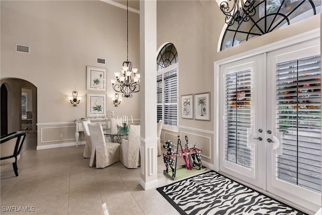 dining area with a towering ceiling, french doors, and light tile patterned floors