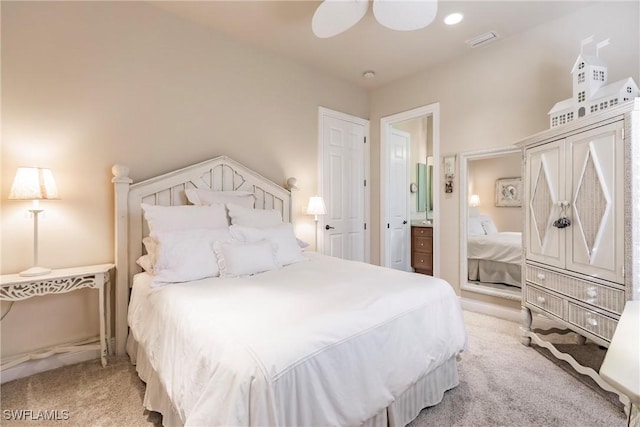 carpeted bedroom with ensuite bath and ceiling fan