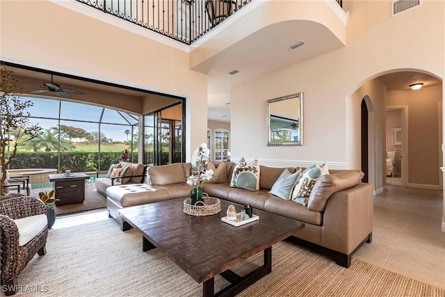 living room with a high ceiling, light tile patterned flooring, and visible vents