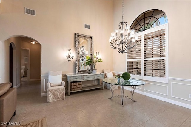 interior space with arched walkways, light tile patterned flooring, visible vents, and a decorative wall