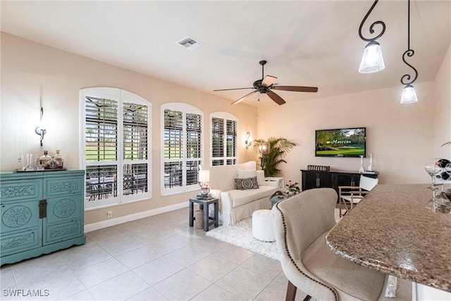 living area with a ceiling fan, visible vents, baseboards, and light tile patterned floors