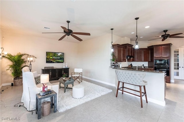 living room featuring a ceiling fan, visible vents, baseboards, and light tile patterned floors