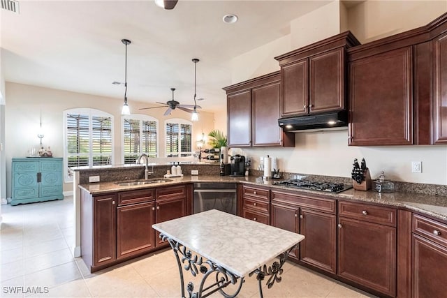 kitchen featuring appliances with stainless steel finishes, a peninsula, under cabinet range hood, pendant lighting, and a sink