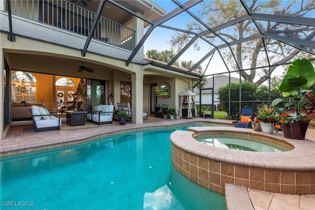 view of pool with glass enclosure, ceiling fan, a patio area, a pool with connected hot tub, and an outdoor living space