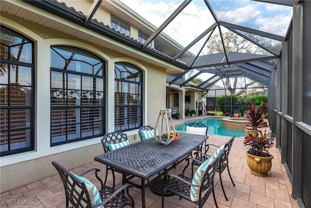 view of patio / terrace featuring glass enclosure and a pool with connected hot tub