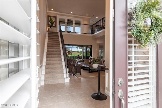 entrance foyer featuring stairway, a high ceiling, light tile patterned flooring, crown molding, and recessed lighting