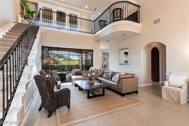 living room with arched walkways, visible vents, baseboards, and light tile patterned floors