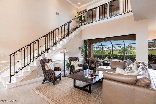 tiled living room featuring a sunroom, visible vents, a decorative wall, and crown molding