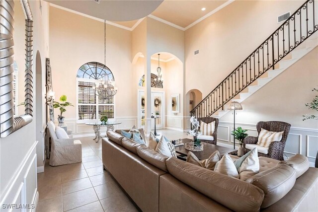 living area featuring arched walkways, light tile patterned floors, a chandelier, a decorative wall, and ornamental molding