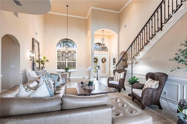 living area with a chandelier, arched walkways, a decorative wall, visible vents, and ornamental molding